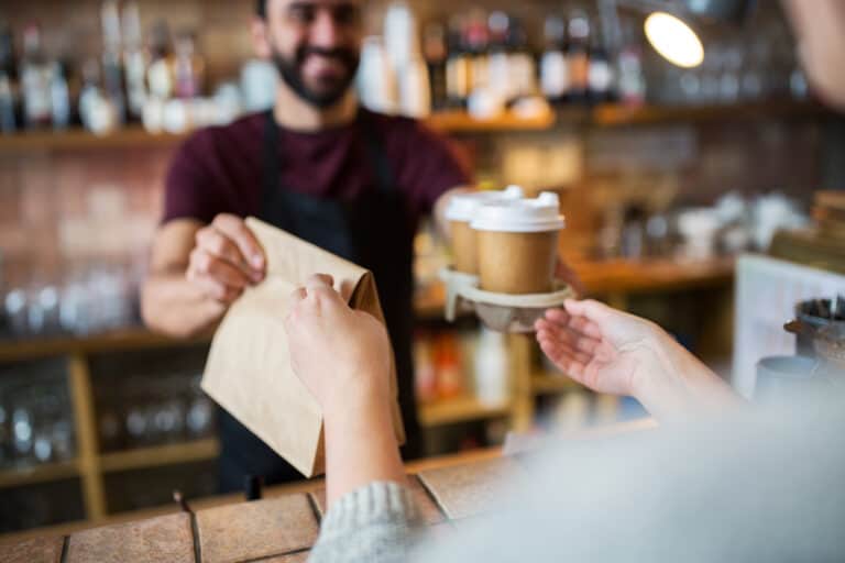 Replay Products | A barista handing a customer a cup of eco-friendly coffee.