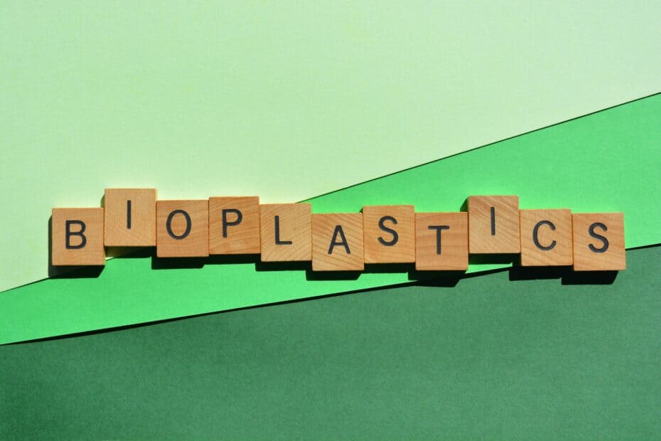 Replay Products | Bioplastics spelled out in wooden blocks on a green background, representing eco-friendly packaging.